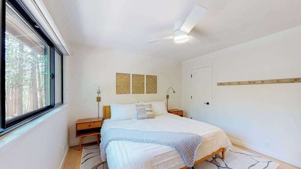 A bedroom with a bed, bedside tables, a ceiling fan, and a window. - Piney Point - Meadowmont (Arnold)