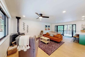 A modern living room with a fireplace, a sofa, a coffee table, and a ceiling fan. - Piney Point - Meadowmont (Arnold)