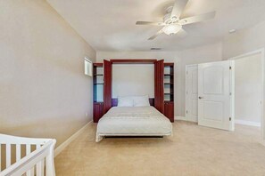 Een slaapkamer met een bed, een plafondventilator en een deur.