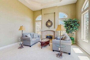A living room with two sofas, a fireplace, a clock, and a large plant. - Hemlock Hacienda - Pine Mountain Lake (Groveland)