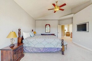 A bedroom with a bed, bedside lamps, a dresser, a ceiling fan, a mirror, and a TV on the wall. - Hemlock Hacienda - Pine Mountain Lake (Groveland)