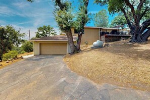 Ein Wohnhaus mit Garage, überdachter Terrasse und einem großen Baum.