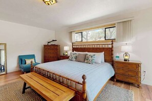 A bedroom with a wooden bed, a bench, a dresser, and a window with curtains. - Walling Mountain Retreat - Pine Mountain Lake (Groveland)