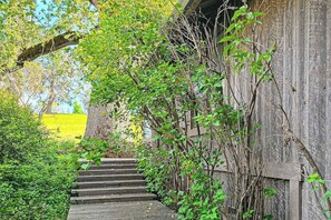 Un escalier en bois mène à un bâtiment rustique entouré de verdure.