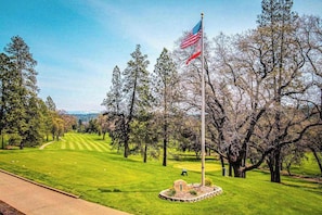 A golf course with a flagpole and flag, surrounded by trees and a clear sky. - Pleasant Pines Retreat - Pine Mountain Lake (Groveland)