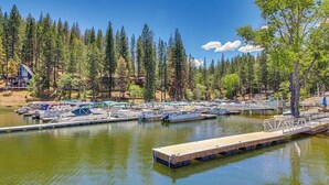 A marina with docked boats, a wooden pier, and a forested backdrop. - Pleasant Pines Retreat - Pine Mountain Lake (Groveland)