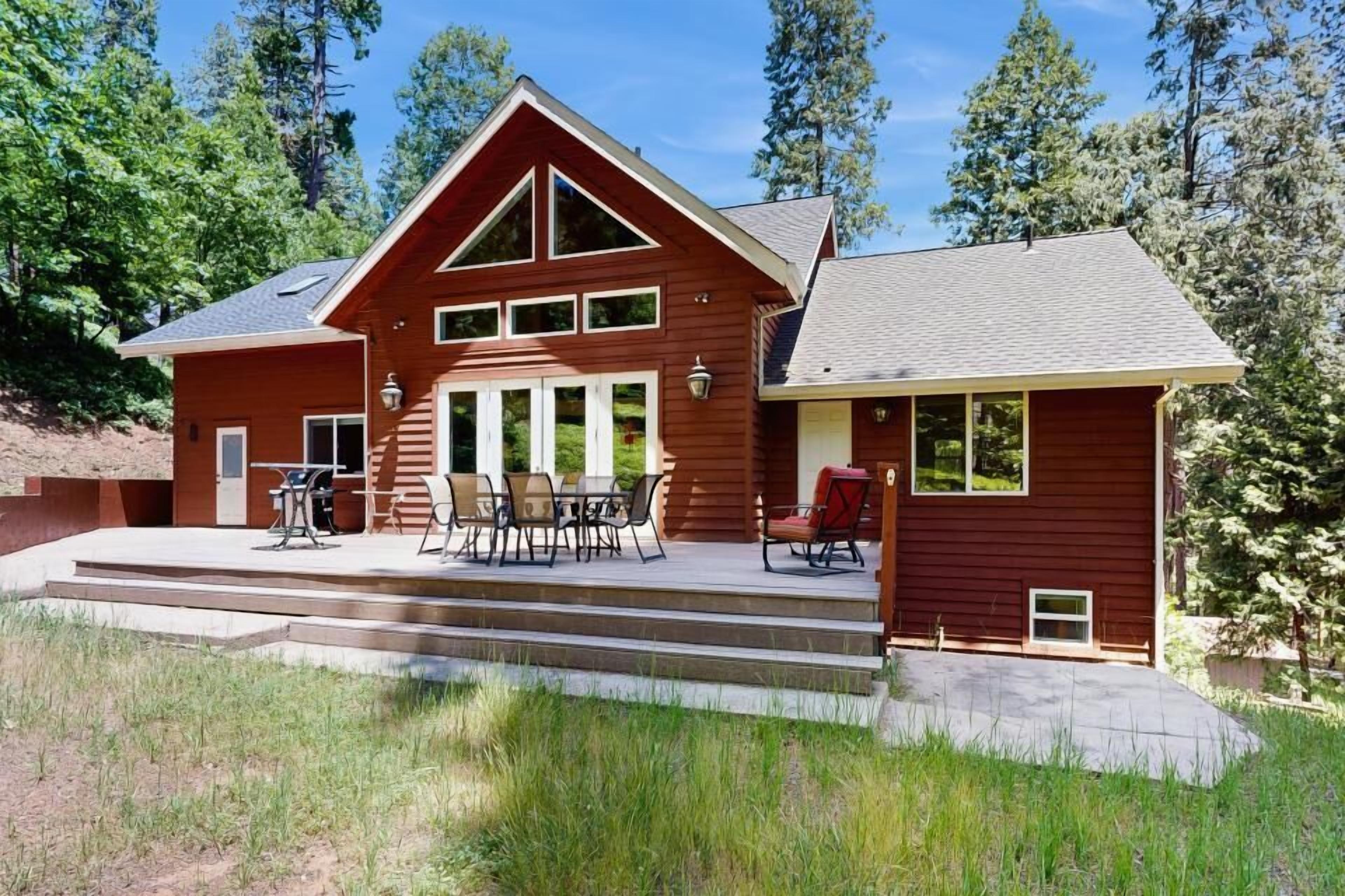 Ein zweistöckiges Holzhaus mit einer überdachten Veranda und einer Sitzgelegenheit im Freien.