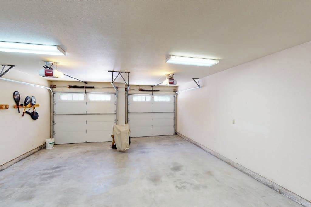 A garage with two double doors, fluorescent lighting, and a concrete floor.