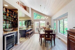 Eine geräumige Küche mit Bar, Holzboden und großen Fenstern mit Blick ins Freie.