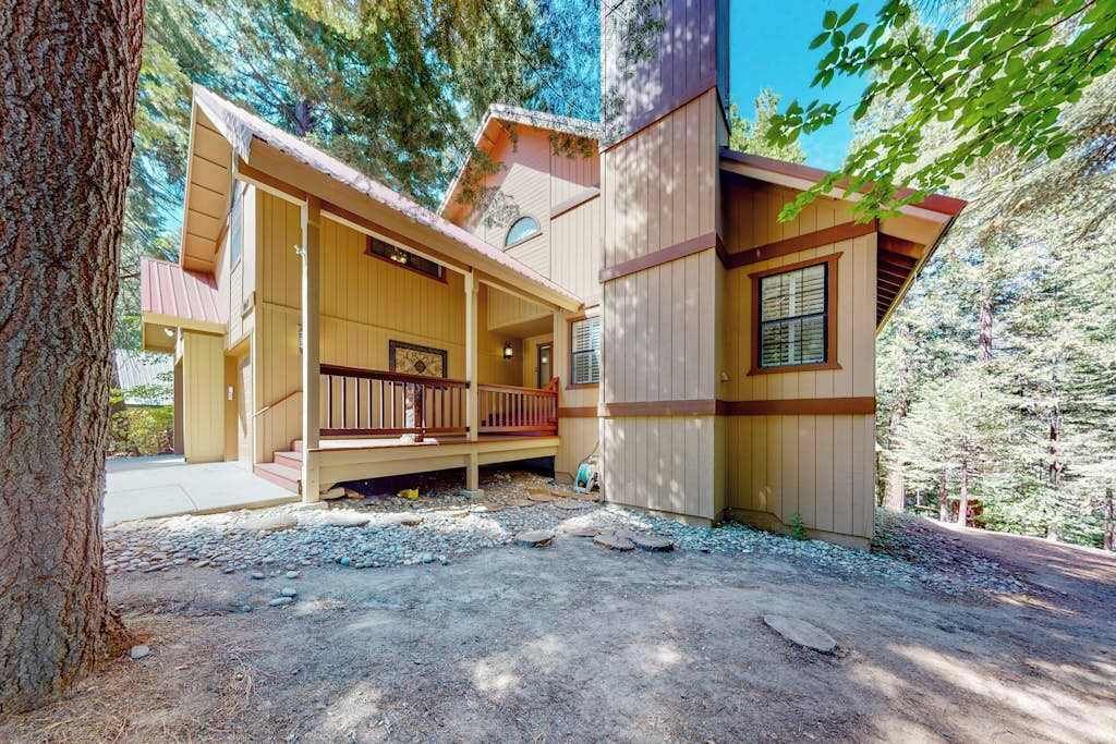 Une cabane en bois avec un porche, entourée d’arbres.
