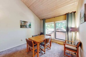 Ein Zimmer mit einem Holztisch, Stühlen, einem Bild an der Wand und einem Fenster mit Vorhängen.
