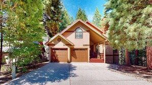 A two-story house with a garage, surrounded by tall trees. - Windwood Inn - Ockenden Ranch (Shaver Lake)