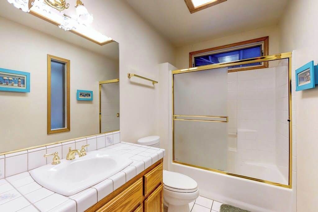 A bathroom with a double sink, toilet, and a glass-enclosed shower.