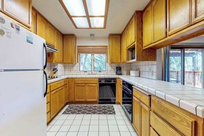 A kitchen with wooden cabinets, a dishwasher, and a window above the sink. - Lake Lodge Retreat - Pine Mountain Lake (Groveland)