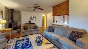 A living room with a fireplace, sofas, a coffee table, and a ceiling fan. - Lake Lodge Retreat - Pine Mountain Lake (Groveland)