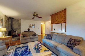 Ein Wohnzimmer mit Kamin, Sofas, einem Couchtisch und einem Deckenventilator.