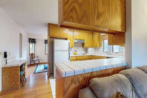 Une cuisine moderne avec des meubles en bois, un îlot central intégré et un réfrigérateur.