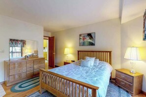Ein Schlafzimmer mit einem hölzernen Bett, einem Schminktisch, einem Nachttisch und einem Bild an der Wand.