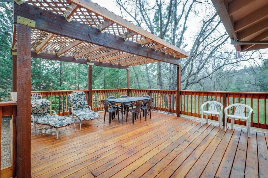 Eine Holzterrasse mit Tisch und Stühlen, umgeben von einem Hollerdgeschoss.