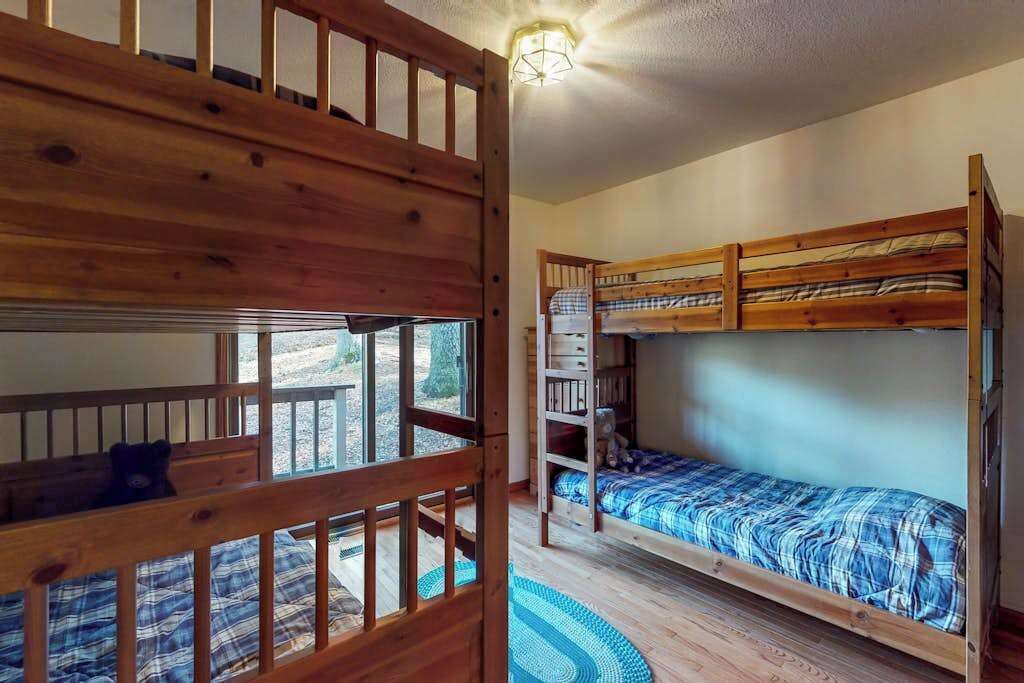 Een kamer met stapelbedden, een houten leuning en uitzicht door een raam.