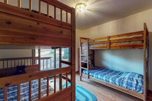 Ein Zimmer mit Etagenbetten, einem Holgeländer und Blick durch ein Fenster.