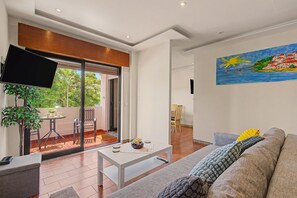 Uma sala de estar moderna com televisão de tela plana, sofá, mesa de centro e um quadro na parede.