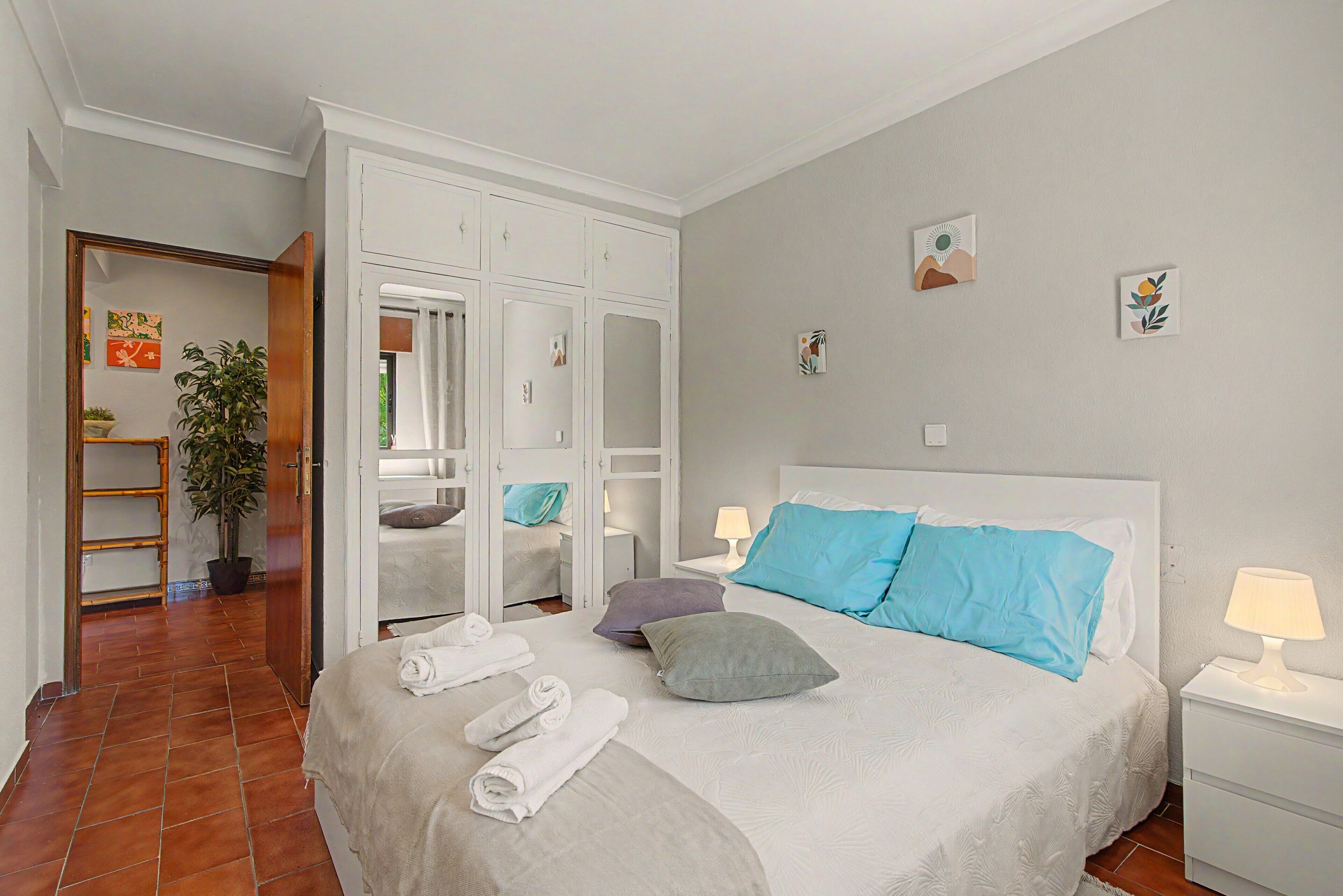 Een hotelkamer met een bed, twee bedlampen, een nachtkastje, een spiegel en een deur naar een badkamer.