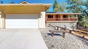 A two-story house with a garage, a covered porch, and a patio area with a bench. - Owl's Lookout - Pine Mountain Lake (Groveland)