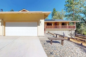 A two-story house with a garage, a covered porch, and a patio area with a bench. - Owl's Lookout - Pine Mountain Lake (Groveland)