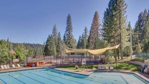 A swimming pool with a shaded area, surrounded by trees and a flag. - Forest Bear's Hideout - Blue Lake Springs (Arnold)
