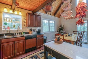 Eine Küche mit Holzschränken, einem Geschirrspüler, einem Spülbecken und einem Essbereich mit Tisch und Stühlen.