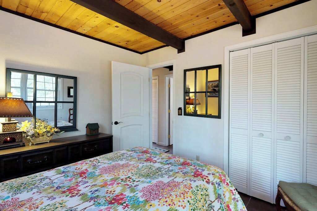 Un dormitorio con cama, cómoda, espejo, armario y ventana.