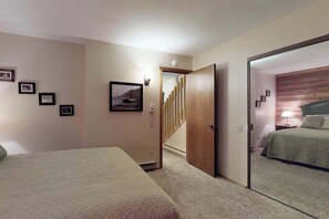 Ein Schlafzimmer mit einem Bett, einer Tür zu einer Treppe und einer Wand mit gerahmten Bildern.