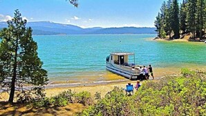 A lake with a boat docked near the shore, surrounded by trees and mountains in the background. - Blue Jay Condominium - Huntington Lake (Lakeshore)