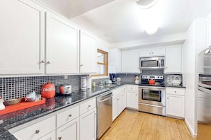 A kitchen with white cabinets, a black countertop, a microwave, an oven, and a dishwasher. - Under The Stars - Shaver Lake (Shaver Lake)