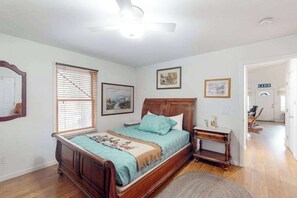 A bedroom with a wooden bed, a nightstand, a ceiling fan, and a window with blinds. - Under The Stars - Shaver Lake (Shaver Lake)