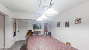 Ein Zimmer mit einem langen Tisch, einer Deckenleuchte und Wandbildern.