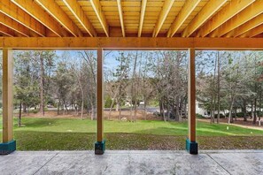 A covered outdoor area with a view of a grassy landscape and trees. - Mule Deer Cabin - Pine Mountain Lake (Groveland)