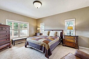 A bedroom with a large bed, two bedside tables with lamps, a bench, and a dresser. - Mule Deer Cabin - Pine Mountain Lake (Groveland)