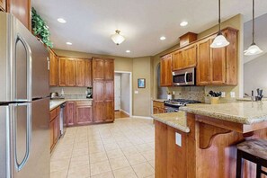 A kitchen with wooden cabinets, stainless steel appliances, and a granite countertop. - Mule Deer Cabin - Pine Mountain Lake (Groveland)