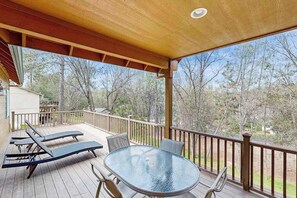 A covered outdoor area with a glass table and lounge chairs. - Mule Deer Cabin - Pine Mountain Lake (Groveland)