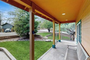 A covered porch with a view of a grassy yard and a road. - Mule Deer Cabin - Pine Mountain Lake (Groveland)