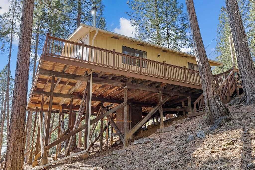 Une cabane en bois dotée d’un balcon, entourée d’arbres.