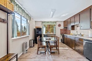 A kitchen with a dining table, chairs, and a brick wall. - Big Trees, Little Cabin - Meadowmont (Arnold)