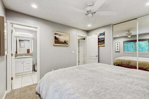 A bedroom with a bed, a ceiling fan, a large mirror, and a window with a view. - Meadowview Cabin - family friendly, W&D (Arnold)