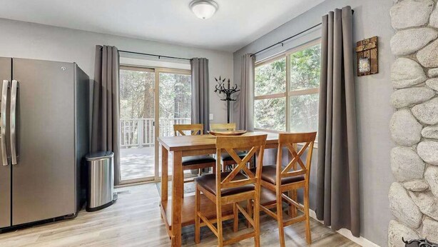 Un comedor con una mesa y sillas, un refrigerador y una pared de piedra.