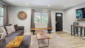 Una sala de estar moderna con un sofá, una mesa de centro, un reloj y un televisor.