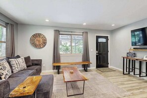 Ein modernes Wohnzimmer mit einer Couch, einem Couchtisch, einer Uhr und einem Fernseher.