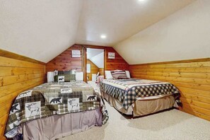 Une chambre avec deux lits, chacun recouvert d’une courtepointe ornée de motifs animaliers.