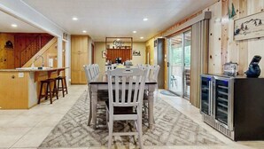 A spacious dining area with a wooden table and chairs, a kitchen with wooden cabinets, and a coffee bar with a sign. - Dorabella Cabin - East Village (Shaver Lake)